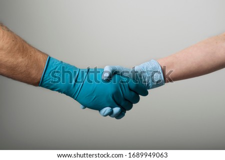 Shaking hands in medical gloves in front of a grey background. Healthcare concept Royalty-Free Stock Photo #1689949063