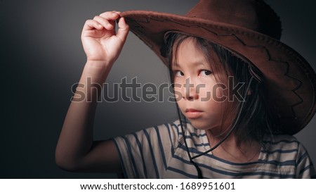 Pretty girl in cowboy hat with gray background.