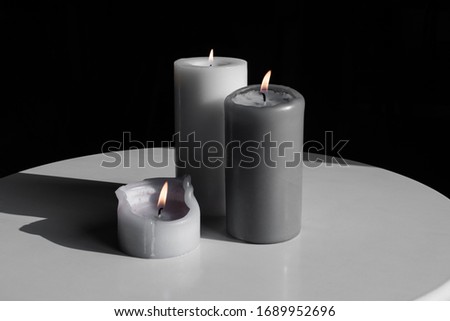 three grey candles on a dark background