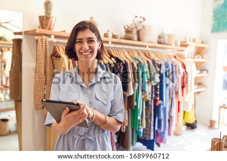 Portrait Of Female Owner Of Fashion Store Checking Stock In Clothing Store With Digital Tablet Royalty-Free Stock Photo #1689960712