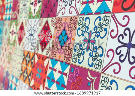 Beautiful colorful set of ornamental ceramic pattern tiles from Portugal. Blurred background. Closeup vertical photo. Selective focus of squares, exterior decoration design concept, angled perspective