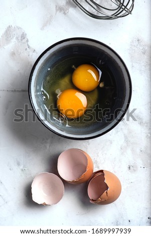 Top view of kitchen table. Bowl with broken eggs and eggs shells on surface. Cooking process Royalty-Free Stock Photo #1689997939