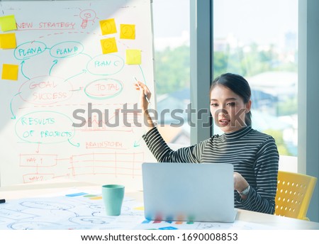 Asian beautiful entrepreneur working and talking video online with laptop and chart board in office or home desk, work at home and social distancing protect coronavirus or covid-19 health care concept Royalty-Free Stock Photo #1690008853