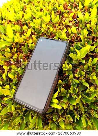 Mobile phone on the ground against a background of green grass. Photos for printing in magazines, posters, banners, advertising products.