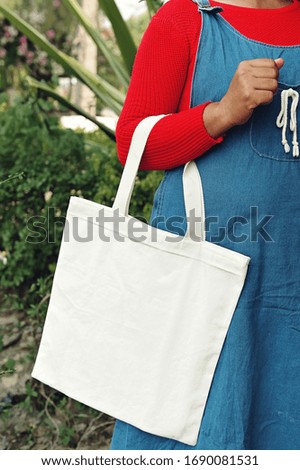 woman holding tote bag with green leaf background