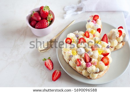 Bunny shaped tart for Easter with fresh strawberry and sugar decorations on marble background, copy space