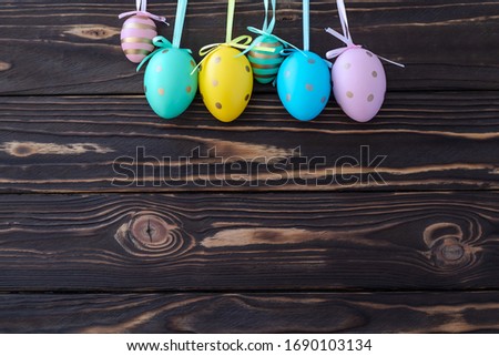 Colorful Easter eggs on dark brown wooden background. Easter gift card, paschal mockup, frame with text space. 