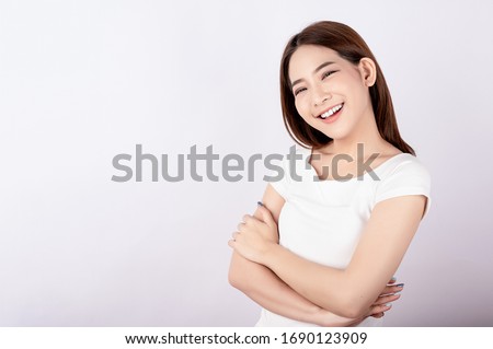 Asian pretty woman in white t-shirt and white pants pretending glad happy face with copy space on white background. Information telling, shopping promotion, announcement, selling support concept. Royalty-Free Stock Photo #1690123909