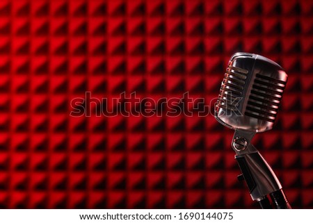 Retro microphone on red acoustic foam panel background