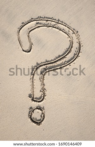 Simple textured question mark drawn by hand on the smooth sand of a sunny beach