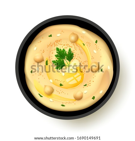 Hummus topped with whole chickpeas, olive oil, sesame, parsley, slices of garlic and sprinkled with paprika and greenery in black bowl with shadow isolated on white background.  Royalty-Free Stock Photo #1690149691