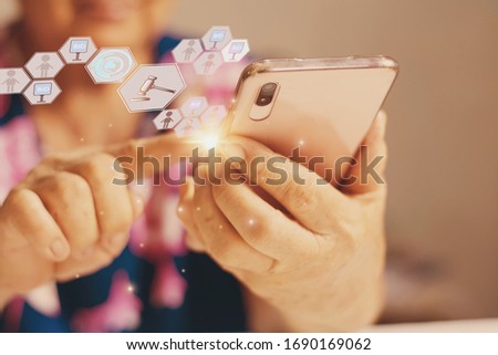Elderly woman use hand holding smart phone enter price bid via wireless network, blue bokeh background with auction icon, Concept online auction via website, application and modern technology