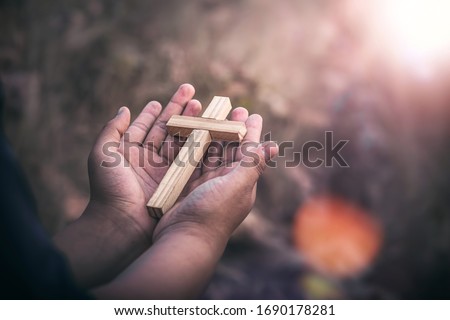 Close up the wooden cross in hands of human, Christian concept background.