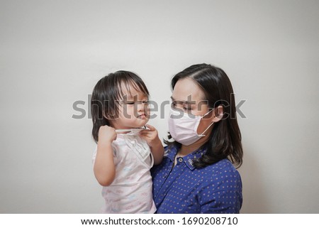 Asian family with kid in face mask, Social distance concept, Mother wearing face mask for protection from covid-19 holds her child in her arms , Coronavirus and Air pollution pm2.5 concept.