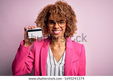 Young african american business woman holding id card identification over pink background with a happy face standing and smiling with a confident smile showing teeth