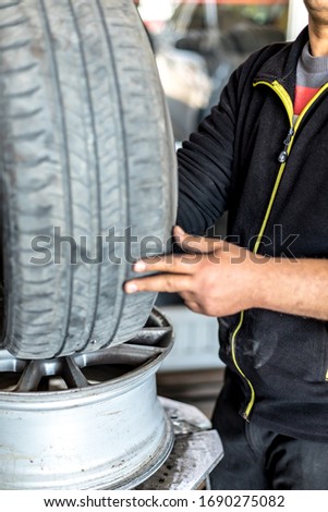 Mechanic with pneumatic wrench unscrews the wheel.Mechanic repairing a car wheel.Male mechanic at a car garage fixing a wheel