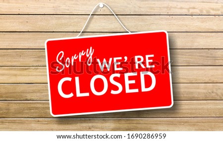 Closed business or store concept. Red color sign board, Sorry we re closed text hanging on store wooden door background,