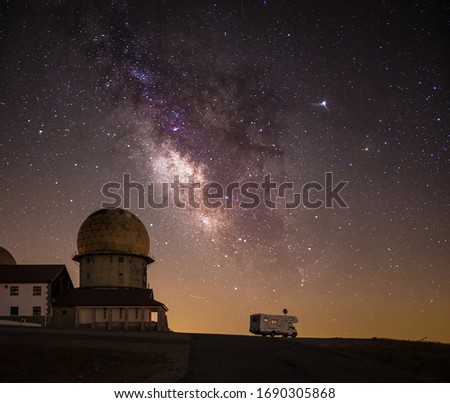 Milky Way galaxy night sky with caravan under stars in beautiful mountain setting
