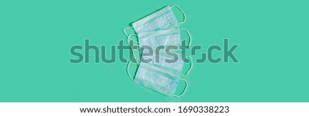 Banner. Blue medical face masks on a green background. A set of medical masks. Medical respiratory bandage face. Prevention of virus, pandemic Covid-19. Quarantine, stay at home.