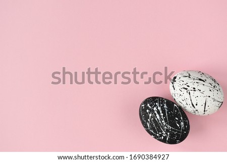 A pair of Easter eggs on a pink background. Painted eggs in black and white.Easter. Black and white.Style minimalism