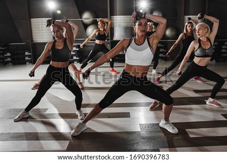 Women in black and white sportswear on a real group body Combat workout in the gym train to fight, kickboxing with a trainer Royalty-Free Stock Photo #1690396783
