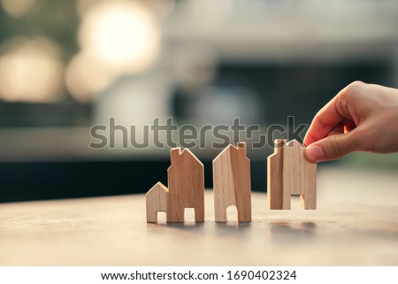 Hand of woman choosing mini wood house model, Planning buy Real Estate, eco house icon concept.