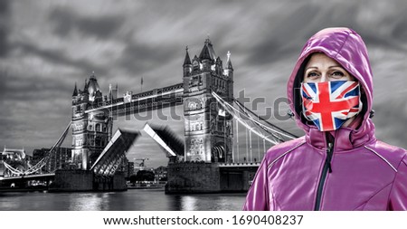 Woman wearing protection face mask with British flag against coronavirus in front of the Tower Bridge, London, England