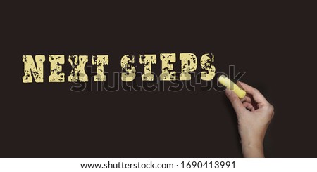 Next steps written with yellow chalk on blackboard. Business startup proccess concept.