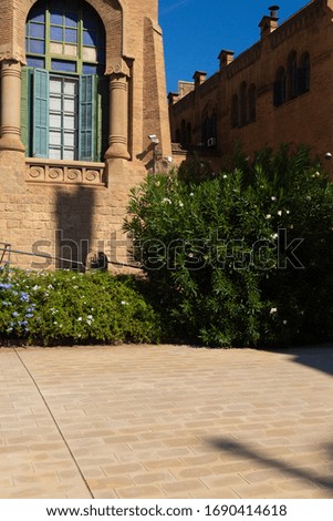 Buildings and walls of red brick, high spiers of the tower and arched windows, elements of architectural decoration of buildings. On the streets in Catalonia, public places.
