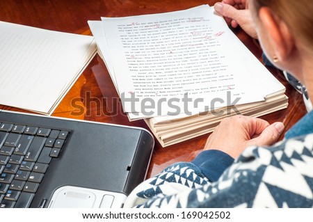 Woman author re-writing her manuscript after it has been proofread by an editor. Royalty-Free Stock Photo #169042502