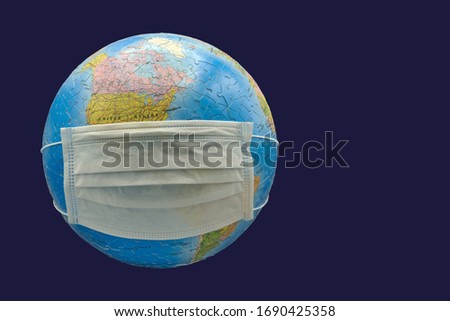 the pandemic keeps the world in breath, earth, earth ball with respirator mask as protection against the corona virus, isolated on blue background, free space for text