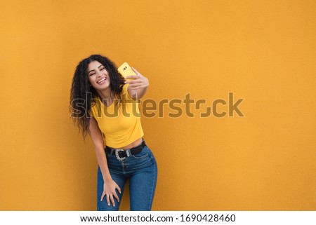 Funny mixed race girl taking selfies pictures with her smartphone