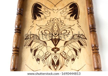 Wooden picture with the image of a wolf made using the technique of pyrography and decorated with a carved frame. On white background