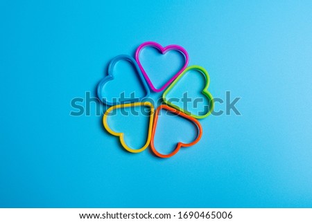 Five colored cookie cutters for making cookies in the form of hearts on a blue background. Culinary concept. Flat lay with copyspace.