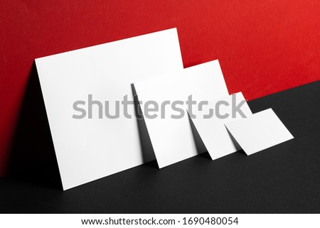 Blank white business cards on red and black paper background, copy space