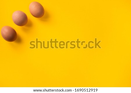 Organic brown chicken eggs on yellow background with copy space and room for text. Easter time.