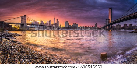 New york skyline reflection on the Hudson river at Brooklyn bridge and Manhattan Bridge at sunset on the shore