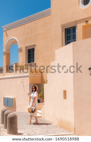 girl in a white dress with glasses on the background of houses on Santorini street