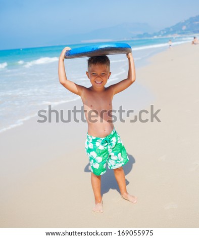 Little surfer. Boy with surfboard runing near ocean.