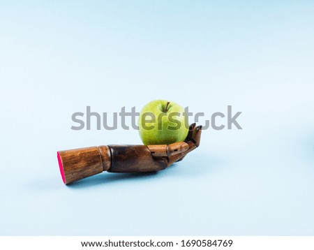 Fresh green apple in palm of wooden hand on blue background