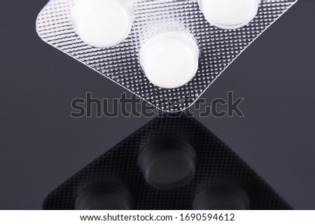 Blister of white round pills on a black background. Pharmaceuticals concept, medical industry. Illustration of a health problem.