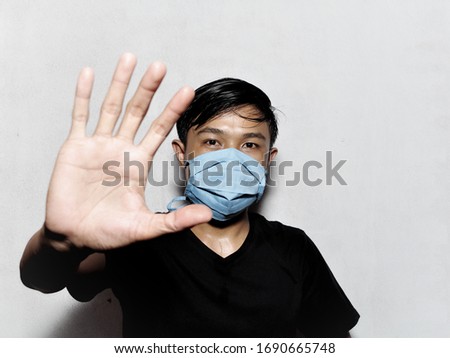 Asian man wearing medical mask show the stop Corona Virus sign. Concept of COVID-19