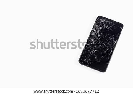 Mobile smartphone with broken touch screen isolated on white background. LCD with many cracks and little pieces of glass. Top view, copy negative space, phone repair concept.
