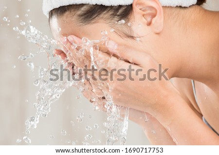 Young woman washing face in room. Royalty-Free Stock Photo #1690717753