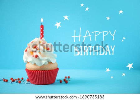 Text Happy Birthday and delicious cupcake with candle on light blue background