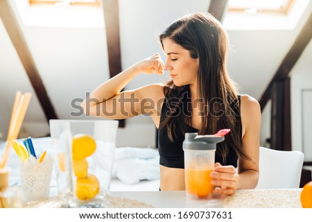 Woman at home drinking orange flavored amino acid vitamin powder.Keto supplement.After exercise liquid meal.Weight loss fitness nutrition diet.Immune system support.Organic citrus fruit drink Royalty-Free Stock Photo #1690737631