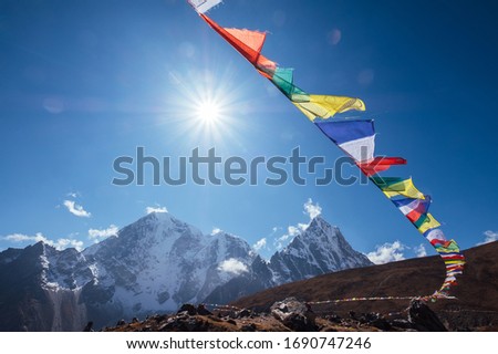 Multicolored Tibetan prayer flags with mantras flapping on the wind with High Himalayas range background. Taboche 6495m and Cholatse 6440m mountains peaks . Everest Base Camp trekking route. Royalty-Free Stock Photo #1690747246