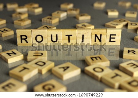 word routine is made up of square wooden letters on a gray background Royalty-Free Stock Photo #1690749229