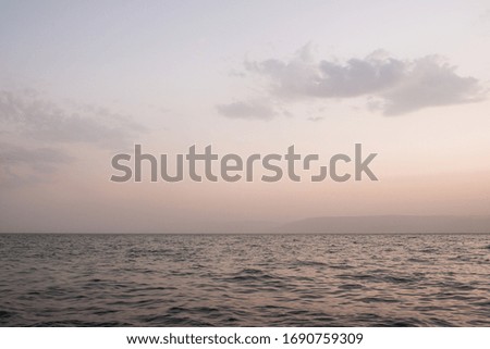 Beautiful sunrise dawn with clouds on the shore of Sea of Galilee, North Israel. Sky and beach stock photo.
