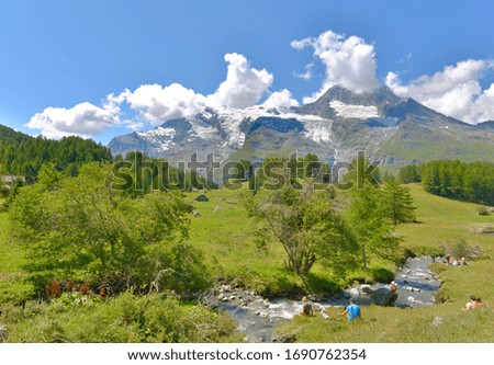 beautiful landscape of european alps in summer with people seatting by the river 
